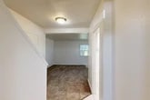 Located in Ovid, NY, this two-story home offers a functional and well-organized layout spread evenly across two floors. The main level features a carpeted living room bathed in natural light from front-facing windows, with a tiled entryway that transitions seamlessly into the living space. The kitchen is equipped with white cabinetry, dark laminate countertops, a stainless steel sink positioned beneath a large window, and a dishwasher. A dedicated laundry area with utility hookups and overhead cabinetry adds everyday convenience. Two bathrooms serve the home, one of which includes a full tub-shower combo with built-in shelving. A staircase leads to the upper level, where both bedrooms are located. The primary bedroom is generously sized and features multiple windows that invite natural light and views of surrounding greenery. The second bedroom is equally bright, with carpeted flooring and a large window. Throughout the home, textured ceilings, clean white walls, and neutral carpet create a simple and cohesive aesthetic. Five closets distributed across both floors provide ample storage, making this home as practical as it is comfortable.
