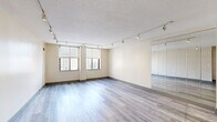 Located at 100 Wells St in downtown Hartford, CT, this one-bedroom, one-bathroom residence offers a practical and comfortable layout across a single floor. Light-toned hardwood flooring runs throughout the main living areas, lending a clean and cohesive aesthetic to the space.

The living room is generously proportioned, featuring dual windows that frame city views and flood the room with natural light. Track lighting runs along the ceiling, offering flexible illumination, while a floor-to-ceiling mirrored wall panel enhances the sense of openness and reflects natural light throughout.

The kitchen is a functional galley-style space finished with granite countertops, gray cabinetry, a tile backsplash, and stainless steel appliances including a gas range and refrigerator. Tile flooring completes the kitchen's clean, practical design.

The bedroom is a well-sized retreat with its own window overlooking the city, hardwood flooring, and ample natural light. A dedicated laundry area with a stacked washer and dryer unit adds significant everyday convenience.

The bathroom is neatly appointed with a tub-shower combination featuring stone-look tile surround, a modern vanity with a white countertop, and tile flooring. A hallway connects the rooms, providing a logical and efficient flow throughout the residence.