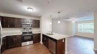 Located in the Hollywood Road Northwest corridor of Atlanta, GA, this single-floor, one-bedroom, one-bathroom residence offers a functional and thoughtfully designed layout. The open-concept living and kitchen area serves as the heart of the home, featuring warm hardwood-style flooring throughout. The kitchen is well-equipped with rich dark-stained cabinetry, light countertops, and a full suite of stainless steel appliances, including a refrigerator, range, microwave, and dishwasher. A peninsula with bar seating and dual pendant lighting above adds both practicality and style, creating a natural gathering space that connects seamlessly to the living area. The bedroom is a comfortable retreat, finished with soft carpet, neutral toned walls, and a window that allows natural light to fill the room. An adjoining walk-in closet provides generous storage with wire shelving along the walls and ceiling. The bathroom continues the consistent design language of the home, featuring hardwood-style flooring, a dark-stained vanity, and clean white finishes. Throughout the residence, a cohesive neutral palette and consistent material choices create a calm, move-in-ready environment suited for everyday living.