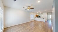 This single-story home in Covington, Louisiana, offers a thoughtfully designed open-concept layout finished with light wood-tone flooring that runs consistently throughout the living areas, kitchen, and bedrooms. The spacious living room is anchored by a ceiling fan with integrated lighting and recessed fixtures overhead, creating a bright, airy atmosphere. Natural light enters through blinds-fitted windows, enhancing the clean, neutral palette of white walls.

The kitchen is functionally appointed with warm-toned wood cabinetry, light countertops, a double-basin sink, and stainless steel appliances including an electric range and over-the-range microwave. A peninsula with bracket-supported overhang extends into the living area, providing casual seating and reinforcing the open flow between spaces.

Each of the three bedrooms features wood-tone flooring, ceiling fans, and windows with natural light. The bedrooms offer comfortable proportions suitable for varied uses. Both bathrooms maintain a consistent design with wood vanity cabinetry, light countertops, tub-shower combinations, and windows that allow natural ventilation. A dedicated interior laundry area accommodates a full-size washer and dryer with overhead shelving for added storage convenience.