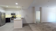 Located at 9800 Mira Lee Way in San Diego's Mira Mesa neighborhood, this single-floor residence offers a clean, contemporary design throughout. The open-concept kitchen is a standout feature, showcasing a striking two-tone cabinet scheme with crisp white upper cabinets and dark lower cabinets, complemented by stainless steel appliances including a range, microwave, and refrigerator. A peninsula with a built-in sink and pendant lighting above provides both functionality and style, seamlessly connecting to the living area. The living spaces feature neutral-toned carpeting, recessed lighting, and a bright, airy atmosphere created by the all-white walls and abundant natural light. The spacious living room flows openly toward the kitchen, offering a comfortable and versatile layout. Bedrooms are well-proportioned, each featuring ceiling fans, carpeted floors, and large windows that invite natural light. One bedroom includes direct access to a private outdoor balcony with views of surrounding greenery, adding an appealing indoor-outdoor connection. The bathrooms are finished with tile flooring, dark vanity cabinetry with white countertops, large mirrors, and a tub-shower combination. A mirrored closet enhances the sense of space in the secondary bathroom area. Overall, the residence presents a modern, move-in-ready aesthetic throughout.