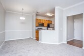 Located at 8186 Veterans Pkwy in Columbus, Georgia, this single-floor residence offers a well-organized and functional layout throughout. The galley-style kitchen is a standout feature, appointed with warm honey-toned cabinetry, granite countertops, hardwood-style flooring, and a full suite of appliances including a range, microwave, and refrigerator. A peninsula with a breakfast bar connects the kitchen to the adjacent living area, providing a convenient pass-through and casual dining space. The open living and dining areas are finished with neutral-toned carpet, crown molding, and ceiling fans, lending a comfortable and cohesive feel to the common spaces. Natural light flows in through multiple windows fitted with blinds, and a glass-panel exterior door in the living room enhances the brightness of the space. The bedrooms are generously proportioned, each featuring plush carpeting, ceiling fans, and ample natural light from well-placed windows. The bathroom is cleanly appointed with tile flooring, a shower-tub combination, and warm wood-toned cabinetry. Throughout the unit, neutral wall tones, white trim, and six-panel doors create a consistent and inviting aesthetic.