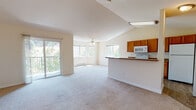 Located at 21200 East Country Vista Drive in Spokane, WA, this single-floor residence offers a well-designed, open-concept layout with a bright and airy atmosphere throughout. The expansive living area is anchored by vaulted ceilings and plush wall-to-wall carpeting, creating a welcoming and spacious feel. Large windows and a sliding glass door flood the space with natural light and provide direct views of the surrounding greenery, while a ceiling fan adds both style and functionality.

The kitchen is thoughtfully designed with warm wood cabinetry, laminate countertops, and wood-style flooring. It is equipped with a full suite of white appliances including an electric range, over-the-range microwave, refrigerator, and dishwasher. A breakfast bar peninsula connects the kitchen to the living area, making it ideal for everyday living and entertaining.

The bedroom is generously proportioned, featuring soft carpeting, multiple windows that invite natural light, a built-in closet, and baseboard heating. The full bathroom includes a double-sink vanity with warm wood cabinetry, a combined tub and shower, a toilet, and wood-style tile flooring. The entry area provides convenient access to the main living spaces, completing this practical and comfortable single-level home.
