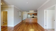 Located at 814 N 3rd St in Wilmington, NC, this single-floor unit offers a well-designed, open layout that maximizes both functionality and comfort. The kitchen serves as the centerpiece of the main living area, featuring warm honey-toned cabinetry, a full suite of stainless steel appliances including a refrigerator, electric range, and built-in microwave, complemented by a tiled backsplash and light stone countertops. A peninsula island with an undermount sink and matching countertop extends the workspace and creates a natural division between the kitchen and the open living area. Rich hardwood flooring runs throughout the main living and kitchen spaces, adding warmth and continuity. The bedrooms offer plush carpeting, neutral wall tones, and windows with blinds that allow for natural light and outdoor views. The bathroom is well-appointed with tile flooring, a combination tub and shower, a wood vanity with stone countertop, and a large mirror. A dedicated laundry area includes a stacked washer and dryer unit alongside additional cabinetry and wire shelving for storage. Crown molding and clean white trim throughout provide a polished, cohesive finish to the space.