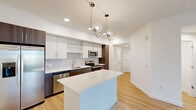 Located at 2085 S Congress Ave in Palm Springs, FL, this well-appointed single-floor home offers four bedrooms and two bathrooms within a thoughtfully designed layout. The open-concept kitchen and living area serves as the heart of the home, showcasing two-tone cabinetry with white uppers and warm walnut-finish lowers, a white quartz countertop island, classic subway tile backsplash, and a full suite of stainless steel appliances. Striking globe pendant lights add a modern touch overhead, while light wood-tone flooring flows consistently throughout the entire home. The primary bedroom features sliding glass doors opening to a balcony with outdoor views, a ceiling fan, and a generous walk-in closet with built-in wire shelving. Additional bedrooms are bright and airy, each equipped with ceiling fans and natural light from well-positioned windows. The primary bathroom offers a glass-enclosed walk-in shower, dual undermount sinks set in a wood-framed vanity with quartz counters, and clean, minimal finishes. The second bathroom features a tiled shower-tub combo and a matching wood vanity. A connecting hallway ties all rooms together, completing this clean, contemporary home.