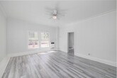 Located at 608 S Westlake in the vibrant Westlake neighborhood of Los Angeles, this single-floor unit offers a thoughtfully organized layout comprising a living room, kitchen, bathroom, two closets, and two hallways — all finished in a crisp, all-white palette that maximizes the sense of openness and light.

The living room serves as the heart of the space, featuring light gray laminate hardwood flooring that runs throughout. Multiple windows invite an abundance of natural light, while a ceiling fan provides year-round comfort. Crown molding along the ceiling adds a refined architectural touch, and a wall-mounted heater offers practical climate control. Views of the surrounding Los Angeles cityscape are visible through the windows, grounding the unit in its urban setting.

Connected via a hallway, the kitchen is efficiently laid out, maintaining the same clean white finishes seen throughout. The bathroom is straightforward and functional, appointed with white tile wall surrounds, a bathtub, and chrome hardware including a towel bar and toilet paper holder, set atop dark wood-toned flooring that provides a subtle contrast. Two closets offer valuable storage. The overall ambiance is bright, clean, and move-in ready, with consistent modern finishes that create a cohesive and welcoming interior.