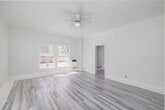 Located at 608 S Westlake in the vibrant Westlake neighborhood of Los Angeles, this single-floor unit offers a thoughtfully organized layout comprising a living room, kitchen, bathroom, two closets, and two hallways — all finished in a crisp, all-white palette that maximizes the sense of openness and light.

The living room serves as the heart of the space, featuring light gray laminate hardwood flooring that runs throughout. Multiple windows invite an abundance of natural light, while a ceiling fan provides year-round comfort. Crown molding along the ceiling adds a refined architectural touch, and a wall-mounted heater offers practical climate control. Views of the surrounding Los Angeles cityscape are visible through the windows, grounding the unit in its urban setting.

Connected via a hallway, the kitchen is efficiently laid out, maintaining the same clean white finishes seen throughout. The bathroom is straightforward and functional, appointed with white tile wall surrounds, a bathtub, and chrome hardware including a towel bar and toilet paper holder, set atop dark wood-toned flooring that provides a subtle contrast. Two closets offer valuable storage. The overall ambiance is bright, clean, and move-in ready, with consistent modern finishes that create a cohesive and welcoming interior.