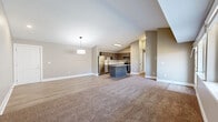 This single-floor residence offers a thoughtfully designed open-concept layout that seamlessly connects the kitchen, dining, and living areas. The kitchen is a standout feature, showcasing dark espresso cabinetry, light quartz countertops, stainless steel appliances including a range, microwave, and refrigerator, and a central island that provides additional prep and storage space. Wood-look flooring runs through the kitchen and entry areas, while plush carpet defines the living room and bedrooms.

The living room benefits from vaulted ceilings that enhance the sense of openness, along with large windows and a sliding glass door that invite abundant natural light and outdoor views. A stylish pendant light anchors the space.

Both bedrooms are comfortably proportioned, carpeted, and feature windows with natural views. The spacious primary bedroom is particularly notable for its generous footprint. Each bedroom is served by a dedicated closet for ample storage.

The two bathrooms are finished with wood-look flooring, dark cabinetry with white countertops, and tub/shower combinations with white tile surrounds and matte black fixtures, delivering a clean, modern aesthetic throughout. A connecting hallway ties all areas of the home together efficiently.