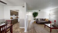 This single-floor residence offers a thoughtfully designed layout that balances open communal areas with comfortable private spaces. The living room is a welcoming focal point, featuring vaulted ceilings, neutral carpet flooring, and a large window that invites natural light and outdoor views. A structural column elegantly separates the living area from the kitchen, adding architectural character to the open-concept design.

The galley-style kitchen is lined with rich, dark wood cabinetry on both sides, providing ample storage and counter space. Wood-look flooring runs throughout the kitchen, complementing the cabinetry and light-toned countertops. The dining area is a defined space finished with matching wood-look flooring, a ceiling fan with light fixture, and a two-tone wall treatment with chair-rail molding that adds a classic touch. A sliding door brings in additional natural light.

The bedrooms are carpeted and generously proportioned, each offering closet storage and room for substantial furniture. One bedroom features an accent wall of textured brick detailing, adding warmth and visual interest, while another includes a walk-in closet. The overall ambiance throughout the home is bright, clean, and functional, with consistent finishes that create a cohesive and inviting atmosphere.