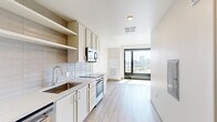 Located at 2601 Alcott St in Denver's LoHi neighborhood, this efficiently designed single-floor unit offers a thoughtful layout comprising a living room, kitchen, hallway, and bathroom. Light hardwood-style flooring flows throughout the living and kitchen areas, creating a cohesive and contemporary aesthetic.

The kitchen is well-appointed with crisp white cabinetry, open shelving, light stone countertops, a subway tile backsplash, stainless steel appliances including a built-in microwave, electric range, refrigerator, and dishwasher, alongside a single-basin undermount sink. The layout maximizes functionality within its compact footprint.

The living area is a standout space, bathed in abundant natural light through floor-to-ceiling sliding glass doors that frame impressive panoramic views of the Denver skyline. A ceiling fan adds comfort to this bright, airy room.

The bathroom features neutral large-format floor tile, a white vanity with an integrated sink, a full-width mirror, and a tiled shower, maintaining the clean, modern style found throughout the unit.

A hallway connects the main areas and includes a closet with a hanging rod for storage. The entry foyer provides a clean transition into the unit. Overall, the space offers a modern, minimalist character with exceptional city views as a defining feature.