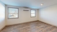 Located at 747 Pontiac Ave in Cranston, Rhode Island, this thoughtfully designed one-bedroom, one-bathroom unit offers a clean, modern aesthetic throughout its well-utilized single-floor layout. Warm wood-look plank flooring runs consistently across every room, creating a cohesive and inviting atmosphere.

The open-concept kitchen and living area serves as the heart of the unit. The kitchen is outfitted with light maple shaker-style cabinetry, white countertops, and a full suite of stainless steel appliances, including a refrigerator, range, microwave, and dishwasher. The adjacent living area benefits from recessed lighting and natural light filtering through windows fitted with blinds.

The generously sized primary bedroom features two windows that bring in ample natural light, a wall-mounted mini-split HVAC unit for individualized climate control, and a double-door closet for convenient storage. Additional rooms include a dedicated laundry space with stacked units and a full bathroom appointed with a glass-enclosed walk-in shower, wood-toned vanity cabinetry, and white countertops. Clean white walls and crisp trim throughout the unit reinforce its fresh, modern character.