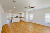 Located at 4400 Chemin Metairie Pkwy in Youngsville, Louisiana, this single-story home offers a thoughtfully designed open-concept floor plan with three bedrooms and two bathrooms. The combined kitchen and living area serves as the heart of the home, featuring warm wood-look flooring, recessed lighting, and a ceiling fan. The kitchen is outfitted with white shaker-style cabinetry, quartz countertops, a subway tile backsplash, stainless steel appliances including a dishwasher and built-in microwave, and a central island with pendant lighting. A hallway with recessed lighting connects the living area to the private quarters, where each bedroom benefits from natural light through white-blinded windows. The spacious primary bedroom includes two windows and access to an en-suite bathroom featuring a white vanity with quartz countertops, matte black fixtures, and a walk-in closet with built-in shelving and a hanging rod. A dedicated laundry room houses a full-size washer and dryer with overhead shelving. The attached garage provides additional storage and parking, complete with an automatic opener. Clean white walls and consistent flooring throughout create a bright, cohesive aesthetic across the entire home.