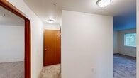 Located at 4034 Idlewild Loop in Coeur d'Alene, Idaho, this one-bedroom, one-bathroom unit offers a well-organized and functional layout across a single floor. The open-concept living, dining, and kitchen area forms the heart of the unit, providing a seamless flow between spaces. The living room features plush carpeting, multiple windows that bring in natural light, a wall-mounted HVAC unit, and direct access to a private balcony with outdoor views. The kitchen is equipped with warm wood-toned cabinetry, light countertops, a double-basin sink, a dishwasher, and hardwood-style flooring, making it both practical and inviting. The bedroom is a comfortably sized retreat with soft carpeting, a large window overlooking the surroundings, and access to two closets for ample storage. The bathroom features a full tub and shower combination with grab bars, a toilet, a vanity, and matching hardwood-style flooring. A dedicated laundry area with a washer and dryer is also included within the unit. A carpeted entry hallway with warm wood-tone doors completes the interior. The overall aesthetic is clean and neutral throughout, offering a move-in-ready foundation.