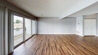 Located at 2010 W Jackson St in Morton, Illinois, this two-floor property offers a well-organized layout with a variety of functional living spaces throughout. The main living area is bright and open, featuring warm hardwood-style flooring and floor-to-ceiling sliding glass doors that lead to a private balcony overlooking a scenic waterfront. The sweeping water views and natural light create an inviting, airy atmosphere throughout the main level.

The kitchen is equipped with warm oak cabinetry offering generous storage, light-toned countertops, a double-basin stainless steel sink, and stainless steel appliances including a range with built-in microwave. The hardwood-style flooring continues seamlessly into the kitchen, maintaining a consistent aesthetic.

The bedrooms are carpeted for comfort and painted in soft neutral gray tones. Each room features sliding glass doors or windows that bring in natural light and offer views of the surrounding area. Closet space is present, and the staircase connecting the two floors is visible from the bedroom level, indicating a well-connected multi-floor layout.

The bathrooms are clean and functional, featuring oak vanity cabinetry, white countertops, mirrored medicine cabinets, and hardwood-style flooring. The overall design is consistent and practical, with a neutral color palette and durable finishes throughout the space.