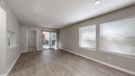 Located at 11251 Alpharetta Hwy in Roswell, GA, this single-floor unit offers a well-designed layout with a consistent, neutral color palette that creates a clean and cohesive atmosphere throughout. The spacious living area is a highlight of the space, featuring smooth wood-look flooring, large windows fitted with blinds that allow for ample natural light, and a sliding glass door that opens directly onto a private patio — ideal for indoor-outdoor living. The kitchen is thoughtfully designed in a galley style, equipped with stainless steel appliances including a refrigerator, range, and dishwasher, complemented by crisp white cabinetry, light countertops, and a subway tile backsplash. Wood-look flooring continues through the kitchen, reinforcing the home's modern aesthetic. The bedrooms offer a contrast in texture with plush carpeting underfoot, neutral walls, and windows that bring in soft natural light — providing a quiet, comfortable retreat. The bathroom corridor features wood-look flooring, a soaking tub, and wall sconce lighting, lending a functional yet refined feel. Throughout the unit, textured ceilings, clean white trim, and consistent finishes tie the space together into a welcoming and move-in-ready residence.