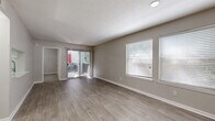 Located at 11251 Alpharetta Hwy in Roswell, GA, this single-floor unit offers a well-designed layout with a consistent, neutral color palette that creates a clean and cohesive atmosphere throughout. The spacious living area is a highlight of the space, featuring smooth wood-look flooring, large windows fitted with blinds that allow for ample natural light, and a sliding glass door that opens directly onto a private patio — ideal for indoor-outdoor living. The kitchen is thoughtfully designed in a galley style, equipped with stainless steel appliances including a refrigerator, range, and dishwasher, complemented by crisp white cabinetry, light countertops, and a subway tile backsplash. Wood-look flooring continues through the kitchen, reinforcing the home's modern aesthetic. The bedrooms offer a contrast in texture with plush carpeting underfoot, neutral walls, and windows that bring in soft natural light — providing a quiet, comfortable retreat. The bathroom corridor features wood-look flooring, a soaking tub, and wall sconce lighting, lending a functional yet refined feel. Throughout the unit, textured ceilings, clean white trim, and consistent finishes tie the space together into a welcoming and move-in-ready residence.