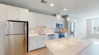 Located at 2008–2032 N Beauregard St in Alexandria, Virginia, this single-floor unit offers a clean, modern aesthetic defined by a neutral color palette, light wood-style flooring, and an open layout that promotes a sense of spaciousness throughout.

The kitchen serves as a central highlight, outfitted with full stainless steel appliances including a refrigerator, range, microwave, and dishwasher. Crisp white cabinetry extends to the ceiling, maximizing storage, while a subway tile backsplash and white quartz countertops contribute to the contemporary design. A freestanding island provides additional prep and dining space, and globe pendant lights overhead add a refined decorative touch.

The living area is open and well-lit, with recessed lighting and neutral walls that create a versatile, move-in-ready environment. Bedrooms are generously proportioned, with at least one featuring a walk-in closet with built-in wire shelving and direct access to a bathroom.

Two bathrooms are present: one features a glass-enclosed walk-in shower and a dual-sink vanity with white cabinetry, while the second includes a tiled soaking tub and single-sink vanity. Both maintain the unit's consistent modern finish throughout.