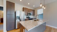 Located at 818 E Long St in Columbus, Ohio, this single-floor residence offers a thoughtfully designed layout with modern finishes throughout. The open-concept kitchen serves as the centerpiece of the home, showcasing rich shaker-style cabinetry, granite countertops, and a large island with an undermount sink—ideal for both cooking and casual dining. Stainless steel appliances, including a French door refrigerator with ice maker, an electric range, and an over-the-range microwave, complement the clean white subway tile backsplash. Industrial-style pendant lighting adds a contemporary touch above the island.

Light hardwood flooring extends throughout the main living areas, creating a warm and cohesive aesthetic, while large windows fitted with blinds invite generous natural light. The adjacent dining and living areas offer an open, airy feel with neutral wall tones that provide a versatile backdrop.

The bedroom features plush wall-to-wall carpeting and dual windows that frame outdoor views, lending a bright and comfortable atmosphere. The bathroom is well-appointed with a granite-topped vanity, wood cabinetry, and a walk-in glass-enclosed shower with built-in shelving, all set on light hardwood flooring. This unit combines practical functionality with modern design for comfortable urban living.