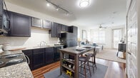 This thoughtfully designed 1-bedroom, 1-bathroom residence offers a cohesive blend of modern style and functional living across a single floor. The open-concept layout connects the kitchen and living room seamlessly, creating a spacious, airy atmosphere. The kitchen is a standout feature, boasting rich dark cabinetry, granite countertops, a classic subway tile backsplash, black appliances, and gleaming hardwood-style flooring. A freestanding island provides additional prep space and casual dining. The living room is bathed in natural light from large windows fitted with white plantation blinds, and features a ceiling fan and plush carpeting for comfort. The bedroom offers a tranquil retreat with a ceiling fan, broad windows with views to the outdoors, soft carpeting, and crisp white walls. A walk-in closet with built-in shelving and dual hanging rods provides generous storage. The bathroom features hardwood-style flooring, dark wood cabinetry, and a soaking tub with a shower. An additional closet completes the unit, ensuring ample storage throughout. The overall ambiance is clean, bright, and modern.