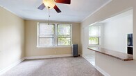 Located at 5123 S Kimbark Ave, this efficiently designed single-floor unit offers a thoughtful layout that maximizes its compact footprint. The living area is carpeted and bathed in natural light from multiple double-hung windows fitted with blinds, providing views of the surrounding greenery. Crown molding lines the ceiling, adding a classic architectural detail, while a ceiling fan with a light fixture ensures year-round comfort. A cast-iron radiator provides supplemental heating, reflecting the building's classic construction. The living space transitions seamlessly into the kitchen via a pass-through counter with granite-style laminate surfaces, creating an open, connected feel. The kitchen is fully equipped with warm wood cabinetry, a U-shaped layout offering ample counter space, a black refrigerator, and white tile flooring. The full bathroom is bright and clean, featuring all-white tile, a single-basin vanity, a soaking tub with shower, a mirrored medicine cabinet, and a window for natural ventilation. A dedicated walk-in closet with wire shelving and a hanging rod provides generous storage. Overall, the space presents a functional and well-maintained layout suited for efficient everyday living.