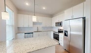 Located at 3240 Champion Ring Rd in Fort Myers, FL, this well-appointed single-story home offers two bedrooms, two bathrooms, and a thoughtfully designed open floor plan. The combined kitchen and living area serves as the heart of the home, showcasing a modern kitchen equipped with crisp white cabinetry, granite countertops, a subway tile backsplash, stainless steel appliances including a refrigerator, electric range, microwave, and dishwasher, and a central island with pendant lighting — ideal for both cooking and casual dining. Light wood-style flooring flows consistently throughout the home, enhancing the bright, clean aesthetic. The spacious primary bedroom connects directly to its own bathroom and features a ceiling fan, while the second bedroom is equally well-lit with a window and ceiling fixture. Both bathrooms are finished with granite-topped vanities and tub/shower combinations. The home includes three closets — one of which is a walk-in with wire shelving — as well as a dedicated laundry area and an outdoor patio. The neutral color palette, recessed lighting, and consistent finishes create a cohesive, move-in-ready environment throughout.