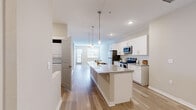 Located at 2830 N Federal Blvd in Denver, CO, this well-appointed one-bedroom, one-bathroom unit offers a thoughtfully designed single-floor layout with a clean, modern aesthetic throughout. Light-toned hardwood-style flooring runs continuously across the space, complementing the neutral warm-beige walls and bright white trim for a cohesive, contemporary feel.

The open-concept kitchen is a standout feature, anchored by a generous granite-topped island with pendant lighting above and an integrated sink. White shaker-style cabinetry lines the walls, paired with stainless steel appliances including a refrigerator, range, and microwave. The kitchen flows seamlessly into the living area, which benefits from natural light through windows fitted with blinds and access to an outdoor area via a glass-paneled door.

The bedroom is a comfortable retreat with its own access to a dedicated walk-in closet outfitted with wire shelving and hanging rods for organized storage. The full bathroom features a soaking tub and shower combination with clean white tile surround and chrome fixtures.

A hallway connects the rooms efficiently, and recessed lighting throughout keeps the space bright and inviting. The overall ambiance is fresh, clean, and move-in ready, ideal for those seeking modern urban living in Denver.