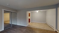 This two-story residence in Pontiac, Michigan offers a well-organized layout across two levels, combining updated finishes with functional design. The entry level welcomes you through a paneled front door into a bright living area featuring durable hardwood-style flooring, neutral painted walls, and a large window dressed with vertical blinds that allows generous natural light to fill the space. A staircase leads to the upper level, and baseboard heating is present throughout for consistent comfort.

The open-plan design connects the living area to an adjoining room with tile flooring and a ceiling fan overhead, creating a versatile space suitable for dining or additional lounging. A sliding mirrored closet door adds both storage and a sense of depth to the area. The kitchen is thoughtfully appointed with warm wood cabinetry, granite-look countertops, a stainless steel sink, and black appliances including a gas range and refrigerator, all set atop tile flooring.

Both bedrooms feature rich hardwood floors, baseboard heating, and wall-mounted air conditioning units for year-round climate control. The full bathroom includes a double vanity with a granite-style countertop, a large mirror, and a shower-tub combination, offering practical elegance throughout.