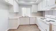 Located at 609 N Chippewa Ave in Anaheim, California, this single-floor unit offers a clean, functional layout spread across several well-defined living spaces. The interior is painted in soft, neutral gray-blue tones throughout, creating a calm and cohesive atmosphere.

The main living area is generously sized with wall-to-wall beige carpeting, a wall-mounted air conditioning unit, and vertical blinds covering a large sliding glass door that allows ample natural light to fill the room. An adjacent area features built-in white upper cabinetry and a countertop pass-through, adding practical storage and workspace.

The kitchen is designed with efficiency in mind, featuring white cabinetry, light stone-patterned countertops, a double-basin sink, a dishwasher, and an electric range, all set atop wood-look vinyl flooring. A window with vertical blinds provides natural light directly over the sink.

The bedrooms are carpeted and feature vertical-blind windows that bring in natural light, offering comfortable, versatile spaces. The bathroom is well-appointed with a white vanity, stone-patterned countertop, a large mirror, a glass-enclosed shower, and wood-look vinyl flooring that ties the space together with a warm, clean aesthetic.