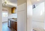Located at 300 Tampa St in Turlock, California, this single-floor residence offers a well-organized layout designed for comfortable everyday living. The galley-style kitchen is a functional highlight, featuring warm wood cabinetry, stainless steel appliances including a refrigerator, electric range, and built-in microwave, along with a double-basin sink and ample counter space. Wood-look flooring runs through the kitchen and connecting hallways, adding a clean, cohesive aesthetic throughout.

The living area is carpeted and bathed in natural light, opening directly onto a private balcony through a full-width sliding glass door with a wood-paneled ceiling overhead. The balcony offers a serene view of a landscaped pond with a fountain, lush greenery, and the surrounding community—a standout feature of this space.

The bathroom includes a full tub-shower combo with chrome fixtures, while an adjacent room features carpeted floors and a walk-in closet with built-in shelving. Additional rooms are finished with neutral-toned walls and carpet, providing versatile spaces adaptable to various needs. The unit also includes a refrigerator accessible from the main hallway corridor. Overall, the space presents a clean, livable environment with appealing outdoor views and practical interior finishes.