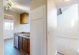 Located at 300 Tampa St in Turlock, California, this single-floor residence offers a well-organized layout designed for comfortable everyday living. The galley-style kitchen is a functional highlight, featuring warm wood cabinetry, stainless steel appliances including a refrigerator, electric range, and built-in microwave, along with a double-basin sink and ample counter space. Wood-look flooring runs through the kitchen and connecting hallways, adding a clean, cohesive aesthetic throughout.

The living area is carpeted and bathed in natural light, opening directly onto a private balcony through a full-width sliding glass door with a wood-paneled ceiling overhead. The balcony offers a serene view of a landscaped pond with a fountain, lush greenery, and the surrounding community—a standout feature of this space.

The bathroom includes a full tub-shower combo with chrome fixtures, while an adjacent room features carpeted floors and a walk-in closet with built-in shelving. Additional rooms are finished with neutral-toned walls and carpet, providing versatile spaces adaptable to various needs. The unit also includes a refrigerator accessible from the main hallway corridor. Overall, the space presents a clean, livable environment with appealing outdoor views and practical interior finishes.