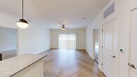 This single-floor residence showcases a cohesive, contemporary design throughout its well-appointed layout. The open living area serves as the heart of the unit, featuring distinctive herringbone-patterned hardwood flooring that adds visual texture and elegance. A ceiling fan with a light fixture provides comfort and illumination, while a large sliding glass door with vertical blinds floods the space with natural light and provides access to an outdoor area.

The kitchen is a functional centerpiece, equipped with rich dark cabinetry, gleaming granite countertops, and a coordinating center island illuminated by stylish pendant lights. Stainless steel appliances—including a refrigerator, range, microwave, and dishwasher—are complemented by a sparkle-tile backsplash that ties the design together seamlessly.

The bedrooms feature plush carpeting and ceiling fans, creating a comfortable retreat atmosphere. Each room benefits from natural light through windows fitted with roller shades. The bathroom is finished with patterned tile flooring, dark cabinetry with granite countertops, an undermount sink with matte black fixtures, and a tub-shower combination. Throughout, the clean white walls and consistent finishes create a bright, unified aesthetic.