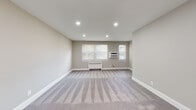 This single-floor space offers a thoughtfully designed layout encompassing multiple living areas, bedrooms, a kitchen, and a bathroom. The living and bedroom areas are finished with plush wall-to-wall carpeting in a neutral gray tone, complementing the warm greige wall color found throughout. Recessed lighting illuminates the larger rooms, while a ceiling fan with integrated light fixture is present in one of the bedrooms. Each carpeted room is equipped with a radiator for heating, and select rooms also feature wall-mounted air conditioning units, ensuring year-round comfort. Windows dressed with white horizontal blinds allow natural light to filter into the rooms. The kitchen is outfitted with gray shaker-style cabinetry, white countertops, stainless steel appliances including a range, microwave, and dishwasher, and a light blue subway tile backsplash, all set atop light-toned tile flooring. The bathroom features a soaking tub with full white three-dimensional textured tile surround and a built-in niche, paired with a window for ventilation. The overall aesthetic is clean, neutral, and move-in ready.
