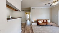 This thoughtfully designed 2-bedroom, 2-bathroom single-floor residence offers a comfortable and functional layout. The open-concept kitchen and living area serves as the heart of the home, featuring hardwood-style flooring, a breakfast bar, and stainless steel appliances including a full-size refrigerator and range. Crown molding throughout adds a polished architectural detail to the neutral-toned walls.

The living room extends to a private outdoor area through French doors that flood the space with natural light. A ceiling fan overhead and plush carpeting underfoot add to the room's comfort and warmth.

The primary bedroom is generously sized, featuring dual windows that invite natural light, a ceiling fan, and soft carpet flooring. A spacious walk-in closet with wire rack shelving provides ample storage. The second bedroom is cozy and well-proportioned, also finished with carpet. Each bedroom is served by its own bathroom, with the bathrooms featuring light wood cabinetry, single vanities, and hardwood-style tile flooring.

Additional highlights include a dedicated laundry area, a central hallway connecting all rooms, and two closets for extra storage. The overall ambiance is clean, bright, and move-in ready.