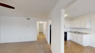 This single-floor residence offers a thoughtfully arranged layout with a clear separation between living, sleeping, and functional spaces. The kitchen is well-appointed with white shaker-style cabinetry, granite-look countertops, a stainless steel sink, and black appliances including a refrigerator, electric range, and range hood — all set atop warm hardwood-style flooring that extends into the adjacent dining area. The dining space benefits from a large window fitted with blinds, allowing natural light to brighten the room and offering views of the surrounding neighborhood. The living area features neutral carpet and connects to a hallway that leads to the bedrooms, providing a natural flow throughout the unit. The bedrooms are carpeted and finished in crisp white tones, each offering windows with blinds for natural light and privacy. One bedroom includes a ceiling fan for added comfort, while spacious reach-in closets provide ample storage. The bathroom is clean and functional, featuring wood-style flooring, a full tub-shower combination with white tile surround, and a toilet. Throughout the space, white walls, consistent trim work, and a neutral color palette create a bright, cohesive atmosphere well-suited for comfortable everyday living.