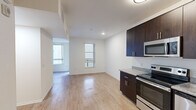 Located on the iconic Sunset Boulevard in the heart of Hollywood, Los Angeles, this efficiently designed unit offers a thoughtful single-floor layout that maximizes every square foot. The open-plan living area is bathed in natural light through multiple windows and features light wood-style flooring that runs throughout, lending a clean, modern aesthetic to the space.

The kitchen is a standout feature, outfitted with rich dark espresso cabinetry extending from floor to ceiling, granite-style countertops, and a full suite of stainless steel appliances including an electric range, built-in microwave, dishwasher, and refrigerator. Ample cabinet storage makes this kitchen as functional as it is visually appealing.

The living area flows seamlessly from the kitchen, offering a versatile open space with crisp white walls and a sliding barn-style door providing access to the bedroom or closet area, adding a contemporary architectural touch.

The bathroom maintains the same cohesive design language, featuring wood-style tile flooring, a full soaking tub and shower combination, a dark-cabinetry vanity with a granite-style countertop, and clean white walls that create a bright, refreshing atmosphere.

This well-appointed unit offers a modern urban lifestyle in one of Los Angeles' most vibrant and sought-after neighborhoods.
