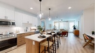 Located at 1455 S Power Rd in Mesa, AZ, this well-appointed 2-bedroom, 2-bathroom home offers a thoughtfully designed single-level open-concept layout. Light wood-tone flooring flows throughout the main living areas, tying together a cohesive and contemporary aesthetic.

The kitchen is a standout feature, showcasing a large center island with a white quartz countertop and seating for multiple bar stools. Two-tone cabinetry — crisp white uppers paired with warm wood lower cabinets — is complemented by stainless steel appliances and stylish glass globe pendant lights. The kitchen opens directly to the dining area and living room, creating a seamless space for entertaining. The living room benefits from natural light through large windows and is finished with a ceiling fan.

Each bedroom is a comfortable retreat, carpeted for warmth, with ceiling fans and windows dressed in blinds and curtains. The primary bedroom is a well-sized private space, and each bedroom is served by its own dedicated bathroom. The bathrooms feature wood-toned vanities with white countertops, black hardware accents, light wood flooring, and walk-in glass-enclosed showers.

Both bedrooms are equipped with generous walk-in closets featuring built-in shelving and hanging rod systems, offering ample organized storage throughout the home.
