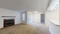 Located at 5270 W 80th Ave in Arvada, Colorado, this single-floor residence offers a functional and straightforward layout designed for comfortable everyday living. The spacious living area is highlighted by a wood-mantled, tile-surround fireplace, serving as a central focal point. Neutral carpet throughout the living and bedroom spaces adds warmth underfoot, while natural light filters in through multiple windows fitted with blinds. A sliding glass door with vertical blinds connects the living area to an exterior access point. The galley-style kitchen features warm wood cabinetry, light countertops, a double basin sink, a coil-top electric range, a dishwasher, and light wood-style flooring, complemented by track lighting overhead. A dedicated laundry area includes washer and dryer hookups for added convenience. The bathroom is outfitted with a full tub-shower combination, wood-style flooring, and clean white fixtures throughout. Additional rooms offer carpeted floors and ample wall space. Textured ceilings are present throughout the home. The overall layout, as seen in the dollhouse view, includes clearly defined living, kitchen, bedroom, and utility areas arranged efficiently across a single level.