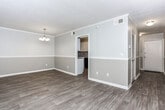 Located at 1261 Woodburn Ct in Columbus, Georgia, this single-story residence presents a thoughtfully updated interior with a neutral, cohesive aesthetic throughout. The layout, visible in the floor plan, includes open living areas, a dedicated kitchen, bedrooms, and a bathroom, all arranged for functional flow.

The main living area features light wood-look flooring, crown molding, and a two-tone gray wall treatment accented by a chair rail. Wall sconces provide warm ambient lighting, and large vertical-blind-covered sliding glass doors allow natural light to filter in while offering outdoor access. An adjacent dining area is distinguished by a classic chandelier and the same refined flooring.

The galley-style kitchen is well-appointed with white shaker cabinetry, granite-look countertops, a tile backsplash, and black appliances including a refrigerator, range, and dishwasher. Crown molding and wood-look flooring continue into this space.

The bedrooms feature plush carpeting, crown molding, wall sconces, and windows that bring in natural light. Closet access is available in each room. The bathroom includes a tiled tub-shower combination, tile flooring, and a granite-topped vanity.

A hallway with wainscoting, crown molding, and a louvered storage door connects the spaces, completing this clean and updated home.