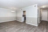 Located at 1261 Woodburn Ct in Columbus, Georgia, this single-story residence presents a thoughtfully updated interior with a neutral, cohesive aesthetic throughout. The layout, visible in the floor plan, includes open living areas, a dedicated kitchen, bedrooms, and a bathroom, all arranged for functional flow.

The main living area features light wood-look flooring, crown molding, and a two-tone gray wall treatment accented by a chair rail. Wall sconces provide warm ambient lighting, and large vertical-blind-covered sliding glass doors allow natural light to filter in while offering outdoor access. An adjacent dining area is distinguished by a classic chandelier and the same refined flooring.

The galley-style kitchen is well-appointed with white shaker cabinetry, granite-look countertops, a tile backsplash, and black appliances including a refrigerator, range, and dishwasher. Crown molding and wood-look flooring continue into this space.

The bedrooms feature plush carpeting, crown molding, wall sconces, and windows that bring in natural light. Closet access is available in each room. The bathroom includes a tiled tub-shower combination, tile flooring, and a granite-topped vanity.

A hallway with wainscoting, crown molding, and a louvered storage door connects the spaces, completing this clean and updated home.