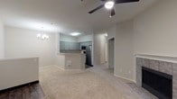 This single-floor residence offers a functional and well-appointed layout designed for comfortable everyday living. The open-concept living and dining area is finished with plush wall-to-wall carpeting and features a ceiling fan with light fixture, a chandelier accent near the entry, and a tile-surround fireplace that serves as a focal point along one wall. A dedicated entry foyer with wood-look flooring transitions smoothly into the living space.

The kitchen is positioned adjacent to the living area and is defined by a raised breakfast bar peninsula. Gray shaker-style cabinetry with granite-look countertops lines the walls, complemented by a full suite of stainless steel appliances, including a refrigerator, electric range, and built-in microwave.

The bedrooms are carpeted and generously proportioned, each equipped with ceiling fans and closet storage. One bedroom benefits from multiple windows overlooking a lush, wooded landscape, filling the room with natural light and serene views.

A bathroom includes gray cabinetry with dark granite-look countertops and wood-look tile flooring. Bifold doors in this area conceal an in-unit washer and dryer, adding a practical convenience to the home's overall design.