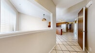 Located at 613 Valley Dr in Emporia, Kansas, this two-story home offers a practical layout across two floors. The main level, which comprises the larger portion of the home, includes an open-concept kitchen and dining area, two hallways, and a bathroom. The kitchen features warm oak cabinetry, a bold tile backsplash, white appliances, and tile flooring, with a pass-through counter connecting it to the dining area. The dining room is brightened by a window with natural light and accented by a decorative pendant light fixture. The main level also includes an entry area with tile flooring and a staircase leading to the upper floor, which features rich hardwood-style flooring with vaulted ceiling angles visible near the stairwell.

The upper level houses three bedrooms and a second bathroom. The bedrooms are carpeted and receive natural light through windows fitted with blinds. One bedroom includes a double sliding-door closet with built-in shelving, offering practical storage. The bathrooms feature tile flooring and tile-surround tub and shower combinations with white vanities. Overall, the home presents a straightforward, functional interior with a neutral color palette throughout.