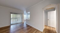 This single-floor unit offers a clean, contemporary layout designed for comfortable everyday living. The open living area is finished with warm wood-look flooring and crisp white walls accented by crown molding, creating a bright and welcoming atmosphere. A full-height sliding glass door fitted with vertical blinds connects the living space to an outdoor area, allowing natural light to flow freely throughout the room.

The kitchen is well-appointed with rich dark-wood cabinetry, white quartz countertops, a subway tile backsplash, and stainless steel appliances including a range, microwave, and sink. A pass-through counter opens the kitchen to the adjacent living and dining area, reinforcing the unit's open and connected feel.

The bedrooms feature wood-look flooring, multiple windows with horizontal blinds that invite natural light, and generous proportions. One bedroom includes a spacious walk-in closet outfitted with wire shelving for ample storage.

The bathroom is finished with a dark-wood vanity, white countertop, framed mirror, and matching flooring. A dedicated in-unit laundry area with a full-size washer and dryer is conveniently accessible from the bathroom, adding practical functionality to the overall layout.