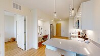 Located at 4640 77th St W in Edina, MN, this modern one-bedroom, one-bathroom unit offers a well-designed open-concept layout with light hardwood flooring and a clean, contemporary aesthetic throughout. The kitchen is a standout feature, outfitted with crisp white shaker cabinetry, quartz countertops, stainless steel appliances including a dishwasher and microwave, a deep undermount sink, and a peninsula with stylish pendant lighting — flowing seamlessly into the living area. The living room is bright and airy, bathed in natural light from a large sliding glass door that opens onto a private balcony with expansive outdoor views of the Edina skyline and surrounding greenery. The bedroom is a comfortable retreat featuring a large floor-to-ceiling window with scenic views, light-toned walls, and hardwood flooring, with access to a dedicated closet equipped with built-in wire shelving. The bathroom includes a full tub-shower combo, white vanity with quartz countertop, and light wood flooring, maintaining the unit's clean and modern feel. A stacked in-unit washer and dryer adds everyday convenience. The unit's neutral palette, modern fixtures, and abundant natural light create a bright, cohesive living environment.