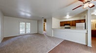 This single-floor residence offers a practical and comfortable layout designed for everyday living. The open-concept main area seamlessly connects the living room and kitchen, where wood-look hard flooring transitions to plush carpet. The kitchen features warm-toned wooden cabinetry, light-colored countertops, and a raised breakfast bar that overlooks the living space. A ceiling fan adds comfort to the living area, which is anchored by a set of French doors that invite natural light and provide access to an outdoor space.

The bedrooms are generously sized and carpeted, each equipped with ceiling fans and natural light from windows with blinds. Sliding closet doors reveal well-organized storage with built-in shelving and hanging rods, offering ample space for wardrobes and personal items.

The bathrooms are clean and functional, featuring white-tiled tub and shower combinations with chrome fixtures, along with wooden vanities topped with light granite-style countertops and undermount sinks. Hard flooring runs throughout the bathroom spaces, adding a cohesive, easy-to-maintain finish. The textured ceilings are consistent throughout the home, contributing to the overall classic residential character of the space.