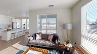 This thoughtfully designed single-floor residence offers a clean, contemporary aesthetic throughout. The open-concept living area is bathed in natural light from large windows with exterior views, and features warm wood-look flooring that flows seamlessly into the kitchen. The kitchen is outfitted with white shaker-style cabinetry, stainless steel appliances including a range, microwave, and refrigerator, complemented by a classic white subway tile backsplash and neutral countertops. The living room provides generous space for relaxing and entertaining, with multiple windows allowing sunlight to pour in throughout the day. Each bedroom is carpeted for comfort and equipped with a ceiling fan, offering a calm and restful atmosphere. The primary bedroom connects to a walk-in closet with built-in shelving and hanging storage. A full bathroom features a glass-enclosed walk-in shower with white tile surround, wood-look flooring, and a modern white vanity with clean-lined hardware. A secondary bathroom mirrors the same refined style with a matching vanity and neutral countertop. Crisp white walls and consistent modern finishes unify the space, creating a cohesive and inviting home environment throughout.