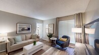 This single-floor residence offers a thoughtfully designed layout that balances comfort and functionality. The living room serves as the heart of the home, featuring warm wood-look flooring, neutral gray walls, and a textured ceiling. Large windows dressed with blinds and curtains flood the space with natural light, while a mix of curated wall art and indoor greenery adds character and warmth.

Adjacent to the living area is a dedicated dining nook, complete with a ceiling fan and its own window, providing a cozy setting for meals and entertaining.

The primary bedroom is a relaxing retreat, finished with plush carpeting, a ceiling fan with lighting, and a generous window that brings in soft natural light. A second bedroom offers equally comfortable proportions, also carpeted and accented with understated décor.

Both bathrooms echo a cohesive design aesthetic, featuring white cabinetry, marble-look countertops, large vanity mirrors with globe lighting, and wood-look flooring. The clean, neutral palette across both bathrooms lends a polished, spa-like atmosphere.

Throughout the residence, the consistent use of soft gray tones, warm wood-look floors in the common areas, and carefully chosen fixtures create a cohesive and inviting ambiance suited for comfortable everyday living.