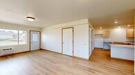 Located on 21st St SE in Menomonie, Wisconsin, this single-floor, 2-bedroom, 1-bathroom home offers a clean and functional layout with consistent light-toned hardwood flooring throughout. The open living room welcomes natural light through a large window and includes a wall-mounted AC unit and a front entry door, creating a bright and airy atmosphere. The well-appointed kitchen features ample light maple cabinetry, stone-patterned countertops, recessed lighting, and a peninsula that adds valuable prep and workspace. Both bedrooms are comfortably sized, each outfitted with ceiling fans and windows that bring in natural light and outdoor views of the surrounding landscape. The primary bedroom includes a spacious reach-in closet, while the second bedroom offers a similarly inviting feel. A hallway connects the main areas of the home with white panel doors trimmed in warm wood accents throughout. The bathroom is clean and functional, featuring a wide vanity with a large mirror, and grab bars near the tub area. The overall aesthetic of the home is bright and neutral, with white walls and warm wood trim detailing providing a welcoming, move-in-ready feel.
