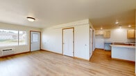 Located on 21st St SE in Menomonie, Wisconsin, this single-floor, 2-bedroom, 1-bathroom home offers a clean and functional layout with consistent light-toned hardwood flooring throughout. The open living room welcomes natural light through a large window and includes a wall-mounted AC unit and a front entry door, creating a bright and airy atmosphere. The well-appointed kitchen features ample light maple cabinetry, stone-patterned countertops, recessed lighting, and a peninsula that adds valuable prep and workspace. Both bedrooms are comfortably sized, each outfitted with ceiling fans and windows that bring in natural light and outdoor views of the surrounding landscape. The primary bedroom includes a spacious reach-in closet, while the second bedroom offers a similarly inviting feel. A hallway connects the main areas of the home with white panel doors trimmed in warm wood accents throughout. The bathroom is clean and functional, featuring a wide vanity with a large mirror, and grab bars near the tub area. The overall aesthetic of the home is bright and neutral, with white walls and warm wood trim detailing providing a welcoming, move-in-ready feel.