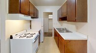 Located at 2426 Blaisdell Ave in Minneapolis, MN, this single-floor unit offers a straightforward and functional layout designed for comfortable everyday living. The spacious living area is carpeted and bathed in natural light through a large window fitted with vertical blinds, complemented by a baseboard heating system and a wall-mounted air conditioning unit for year-round climate control. The galley-style kitchen is efficiently arranged with warm wood-toned cabinetry on both sides, light countertops, a double-basin sink, and white appliances including a gas range and refrigerator. A doorway from the kitchen connects to an adjacent area, enhancing the overall flow of the unit. The bedroom is generously sized with soft carpeting, a wide window with vertical blinds, and a full-width closet with a hanging rod for ample storage. A hallway with textured ceilings connects the main living spaces and features additional door access points. The bathroom includes a full tub and shower combination with clean white tile surround and chrome fixtures. Throughout the unit, neutral white walls, textured ceilings, and consistent carpeting create a cohesive and move-in-ready environment well-suited for Minneapolis living.