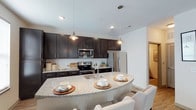 This two-floor residence is designed with a contemporary aesthetic and functional layout throughout. The kitchen serves as a central highlight, outfitted with rich dark cabinetry, light granite countertops, a white subway tile backsplash, and a full suite of stainless steel appliances including a range, microwave, and refrigerator. A curved granite-topped island with pendant lighting provides additional seating and workspace, making it ideal for both cooking and casual dining.

The dining area features light hardwood-style flooring, a stylish pendant light fixture, and ample wall space for décor, creating an inviting setting for meals. The living room is generously sized with large windows that allow natural light to fill the space, complemented by a ceiling fan and hardwood-style flooring that ties the main living areas together.

The bedrooms offer plush carpeting, ceiling fans, and multiple windows dressed with blinds and curtains, providing comfort and privacy. The bathrooms are finished with dark vanity cabinetry, granite countertops, framed mirrors, and wood-look flooring. One bathroom includes a soaking tub and shower combination, while another features a single vanity with well-lit mirror.

A dedicated laundry area with a full-size washer and dryer adds everyday convenience, rounding out this thoughtfully designed multi-floor home.